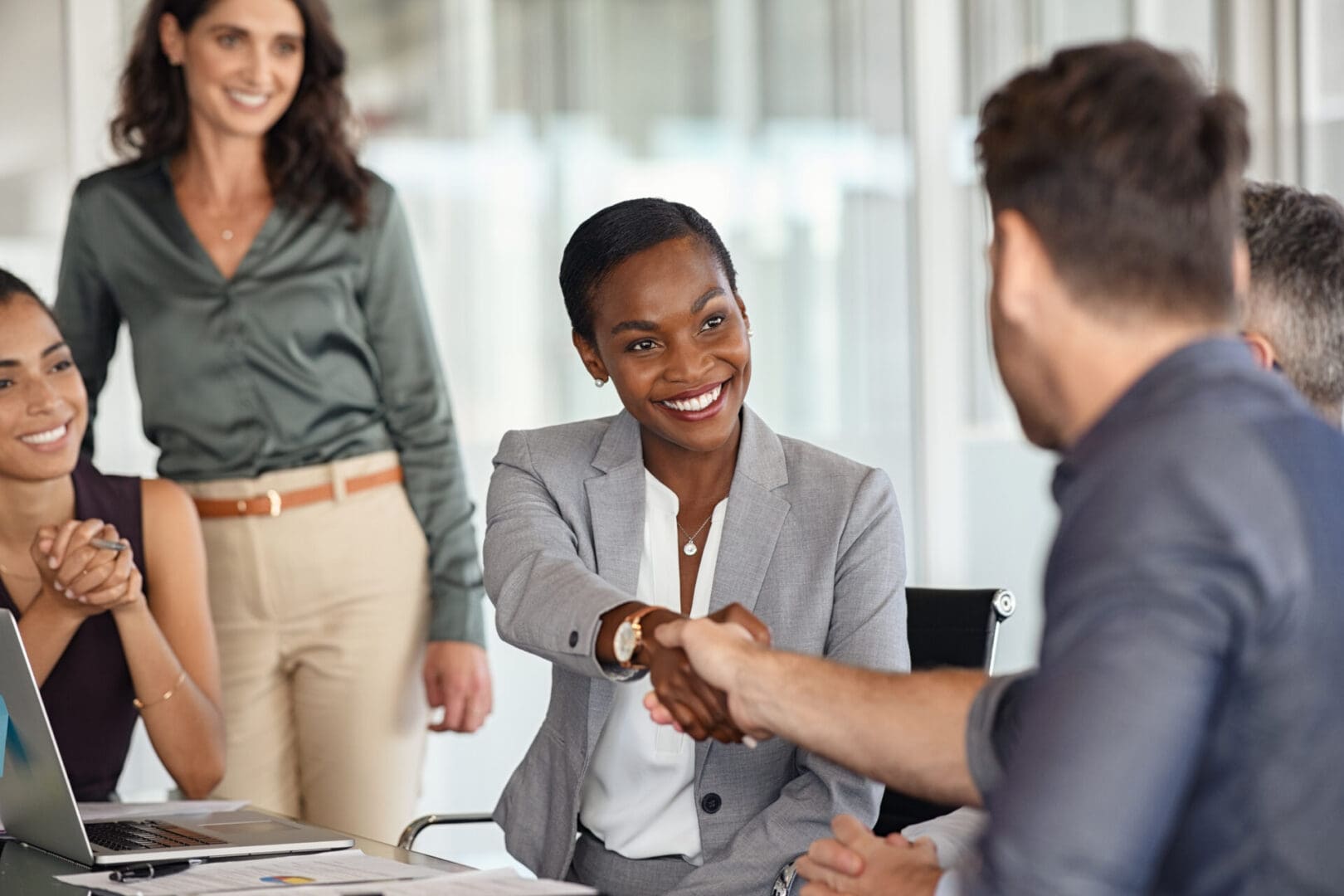 A woman and man shaking hands in front of another man.